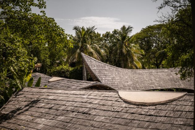 Les toitures des ateliers en tuiles de bambou fendues s'intègrent dans la végétation tropicale // Satcha, Cambodian Handicraft Incubation Center / Topophile