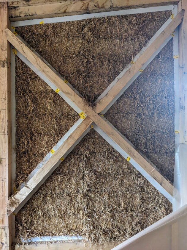 Entre la structurures porteuses en bois massif et les bottes de paille, des bandes de fibro-gypse sont insérés pour assurer l'étanchéité à l'air une fois l'enduit appliqué // Martin Paquot / Topophile